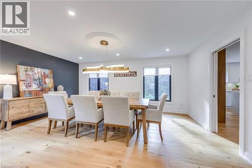 Dining area featuring wide plank wood-finish flooring, recessed lighting, and a contemporary chandelier - 54 Deerview Avenue, Ancaster, ON - Indoor Photo Showing Dining Room