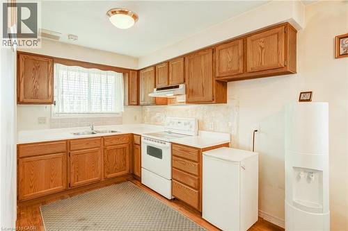 Kitchen featuring wood-finish cabinetry, a double basin stainless steel sink, and white countertops - 186 Adeline Avenue, Hamilton, ON - Indoor Photo Showing Kitchen With Double Sink