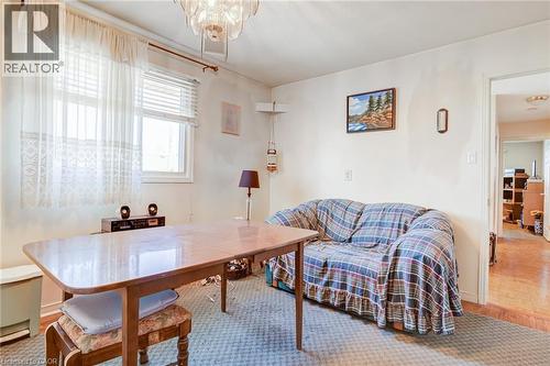 Carpeted room with a central wooden table and a decorative chandelier - 186 Adeline Avenue, Hamilton, ON - Indoor