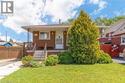 Brick exterior with a covered front porch, concrete steps, and wrought iron railings - 186 Adeline Avenue, Hamilton, ON - Outdoor
