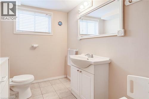Bathroom featuring a window with horizontal blinds, a vanity with an integrated sink, a large wall-mounted mirror, and tile flooring - 186 Adeline Avenue, Hamilton, ON - Indoor Photo Showing Bathroom