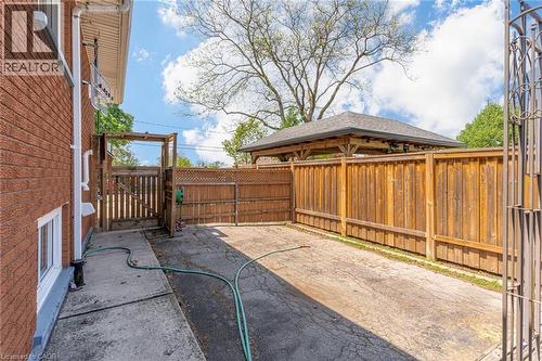 Paved side yard featuring a wood fence, wood gate, and a covered structure - 186 Adeline Avenue, Hamilton, ON - Outdoor