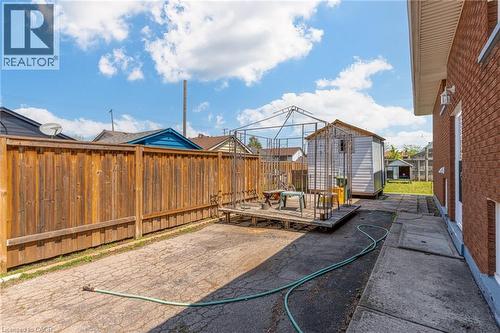 Expansive backyard with a full privacy fence, paved patio area, and a utility shed - 186 Adeline Avenue, Hamilton, ON - Outdoor