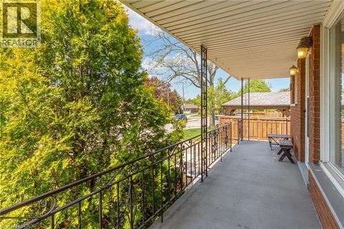 Covered porch featuring a concrete surface, decorative wrought iron railing, and brick exterior wall - 186 Adeline Avenue, Hamilton, ON - Outdoor With Exterior