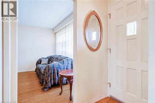 Entryway featuring a paneled door with a glass insert, a decorative oval mirror, and wood-finish flooring extending into the room - 186 Adeline Avenue, Hamilton, ON - Indoor Photo Showing Other Room