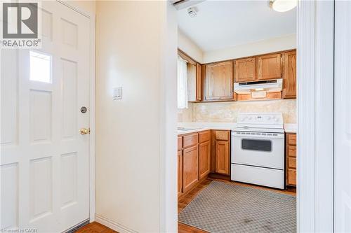 Kitchen area featuring wood cabinetry, white countertops, white electric range, and a white range hood - 186 Adeline Avenue, Hamilton, ON - Indoor Photo Showing Kitchen