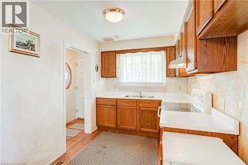 Kitchen with wood-finish cabinetry, white countertops, a tiled backsplash, and a built-in range - 186 Adeline Avenue, Hamilton, ON - Indoor Photo Showing Kitchen With Double Sink