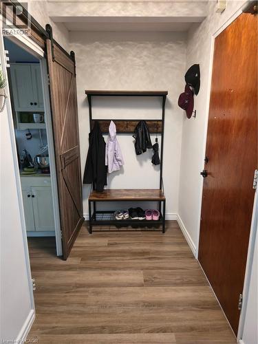 Wood-finish flooring throughout, complemented by a sliding barn door with dark hardware - 45 Westmount Road N Unit# 202, Waterloo, ON - Indoor