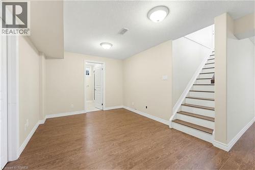 Expansive room featuring wood-finish flooring, neutral-toned walls, a staircase with white risers and dark treads, and a doorway leading to an additional space - 6 General Street, Brantford, ON - Indoor Photo Showing Other Room