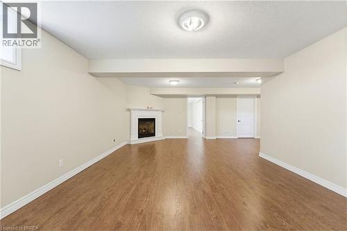 Spacious room featuring wood-finish flooring, light-toned walls, and white baseboards - 6 General Street, Brantford, ON - Indoor With Fireplace