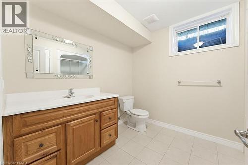 Bathroom featuring a wooden vanity with a white countertop, a decorative mirror, a toilet, and a window - 6 General Street, Brantford, ON - Indoor Photo Showing Bathroom
