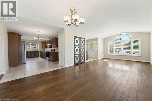 Spacious main living area featuring wide plank wood-finish flooring, a vaulted ceiling, and a large arched window with plantation shutters - 6 General Street, Brantford, ON - Indoor