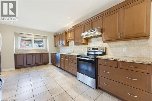 Kitchen featuring extensive cabinetry, tile flooring, stainless steel appliances, granite countertops, and a subway tile backsplash - 6 General Street, Brantford, ON - Indoor Photo Showing Kitchen