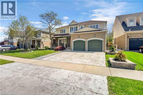 Two-story residence featuring a two-car garage with arched entrances, a patterned concrete driveway, and front-facing dormer windows - 69 Hunter Way, Brantford, ON - Outdoor With Facade