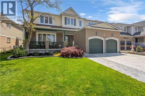 Brick facade residence featuring a covered front porch, a two-car garage with arched entrances, and a patterned concrete driveway - 69 Hunter Way, Brantford, ON - Outdoor With Deck Patio Veranda With Facade