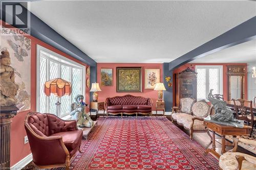 Spacious interior room featuring decorative picture windows, a detailed chandelier, and wood-finish flooring partially covered by a large area rug - 69 Hunter Way, Brantford, ON - Indoor Photo Showing Living Room