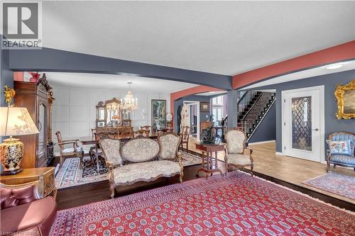 Expansive interior showcasing hard surface flooring, a built-in staircase with wrought iron railing, a white entry door with decorative glass, and a dining area with wainscoting - 69 Hunter Way, Brantford, ON - Indoor Photo Showing Living Room