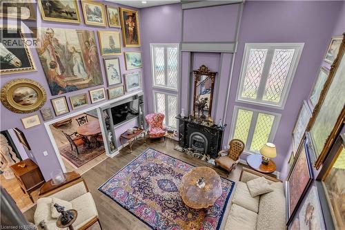 Two-story living area with wood-finish flooring, a black marble fireplace, and multiple tall, diamond-pane windows - 69 Hunter Way, Brantford, ON - Indoor With Fireplace