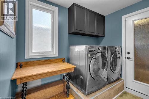Dedicated laundry area featuring a white framed window, overhead cabinetry, and wood-finish flooring - 69 Hunter Way, Brantford, ON - Indoor Photo Showing Laundry Room
