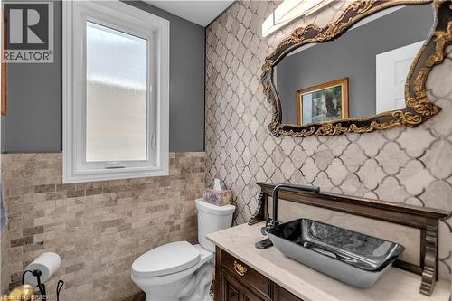 Bathroom featuring a decorative vanity with a vessel sink, an ornate framed mirror, and extensive wall tiling - 69 Hunter Way, Brantford, ON - Indoor Photo Showing Bathroom