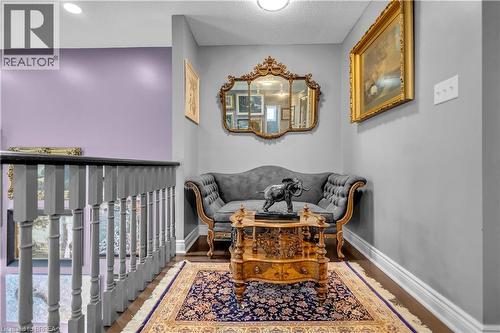 Hardwood flooring in a hallway alcove featuring a decorative area rug, chair rail molding, and a balustrade - 69 Hunter Way, Brantford, ON - Indoor Photo Showing Other Room