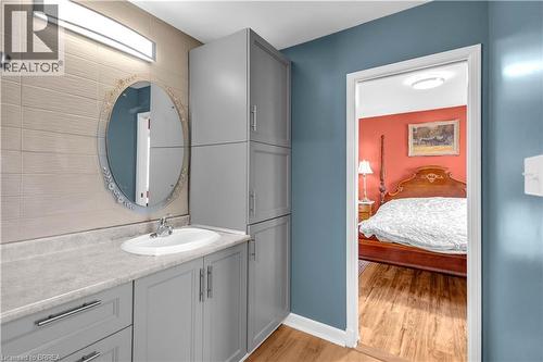 Bathroom vanity featuring a light grey countertop, an oval mirror, and a wall-mounted light fixture - 69 Hunter Way, Brantford, ON - Indoor Photo Showing Bathroom