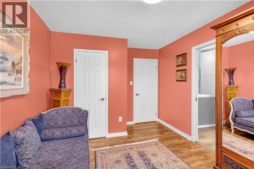 Interior hallway with wood-finish flooring, two panel doors, and a bathroom entrance featuring a vanity with a sink - 69 Hunter Way, Brantford, ON - Indoor