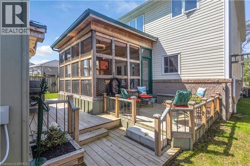 Expansive multi-level wood deck featuring a screened-in porch with wood-finish ceiling, outdoor lighting fixture, and a glass-paneled entry door - 69 Hunter Way, Brantford, ON - Outdoor With Deck Patio Veranda