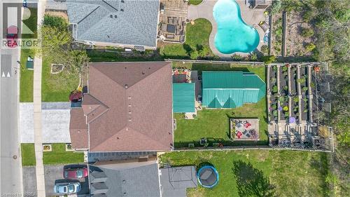 Expansive backyard featuring a green metal-roofed structure, raised garden beds, a concrete patio, and a fire pit area - 69 Hunter Way, Brantford, ON - Outdoor With View