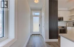 Foyer with wood-finish flooring, a white-framed window, and a frosted glass entry door - 