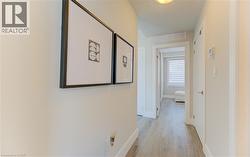 Hallway featuring wood-finish flooring, light neutral wall tones, white trim, and a contemporary flush-mount ceiling light - 