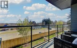 Outdoor balcony featuring glass panel railings with black framing, a concrete floor, and horizontal siding on the building exterior - 