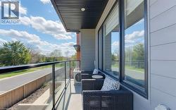 Private balcony featuring a glass railing with a dark top rail, offering an open-air extension of the living space - 