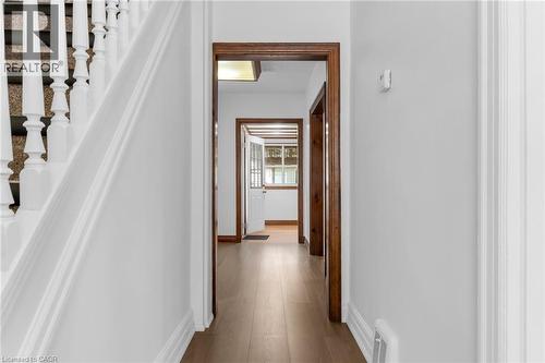 Hallway featuring light wood-finish flooring, white painted walls, and warm wood door frames - 168 Britannia Avenue, Hamilton, ON - Indoor Photo Showing Other Room