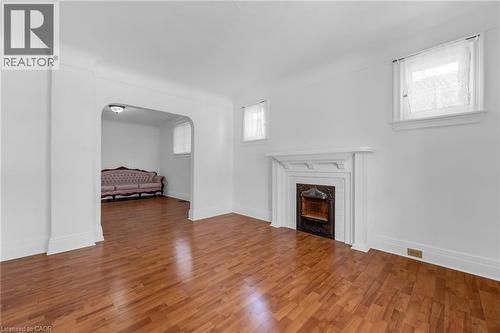 Spacious interior room featuring wood-finish flooring, a traditional white mantel with a dark fireplace surround, and multiple windows - 168 Britannia Avenue, Hamilton, ON - Indoor With Fireplace