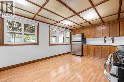 Kitchen space featuring wood-finish flooring, two windows with white blinds, and a paneled ceiling - 168 Britannia Avenue, Hamilton, ON - Indoor