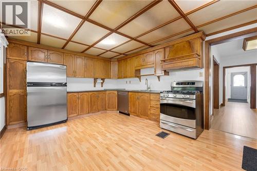 Kitchen featuring wood-finish flooring, extensive wood cabinetry, stainless steel appliances, and a coffered ceiling - 168 Britannia Avenue, Hamilton, ON - Indoor Photo Showing Kitchen