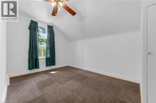 Attic room featuring a window with natural light, a ceiling fan, white baseboards, and patterned carpet flooring - 168 Britannia Avenue, Hamilton, ON - Indoor Photo Showing Other Room