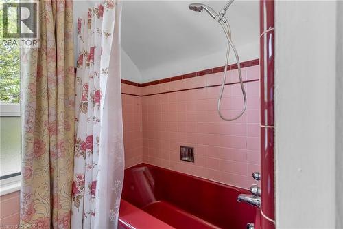 Pink tile surround with contrasting dark red accent trim and a red bathtub - 168 Britannia Avenue, Hamilton, ON - Indoor Photo Showing Bathroom