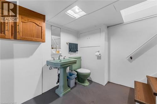 Bathroom featuring a pedestal sink, toilet, wall-mounted mirror, and built-in wood cabinetry - 168 Britannia Avenue, Hamilton, ON - Indoor