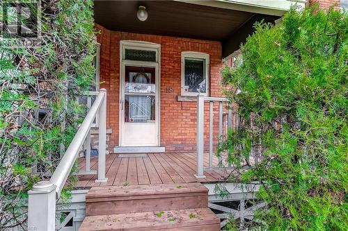 Brick facade home featuring a wood deck entry with white railings, wood steps, and mature evergreen shrubs - 18 Fairleigh Crescent, Hamilton, ON - Outdoor