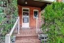 Brick facade home featuring a wood deck entry with white railings, wood steps, and mature evergreen shrubs - 18 Fairleigh Crescent, Hamilton, ON  - Outdoor 