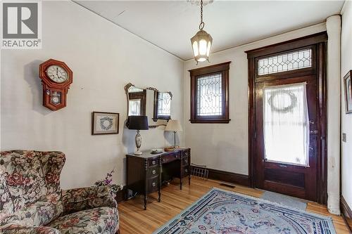 Entryway featuring a rich wood-finish door with leaded glass transom and side window, hardwood flooring, and a pendant light fixture - 18 Fairleigh Crescent, Hamilton, ON - Indoor