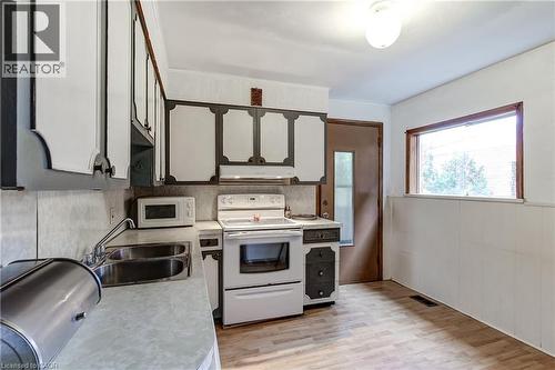 Kitchen featuring overhead and base cabinetry, double basin stainless steel sink, and white appliances - 18 Fairleigh Crescent, Hamilton, ON - Indoor Photo Showing Kitchen With Double Sink