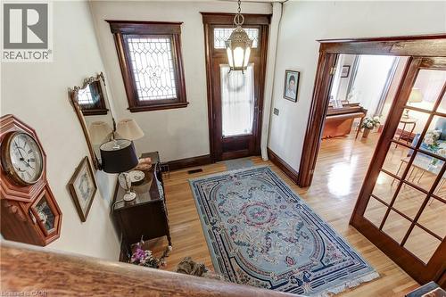 Foyer featuring hardwood flooring, an ornate front door with glass paneling, a leaded glass window, and a decorative overhead light fixture - 18 Fairleigh Crescent, Hamilton, ON - Indoor Photo Showing Other Room