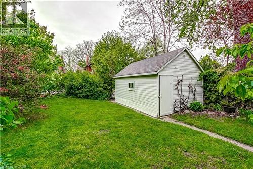 Expansive green lawn with a white wood-sided shed featuring a single door and small window - 18 Fairleigh Crescent, Hamilton, ON - Outdoor