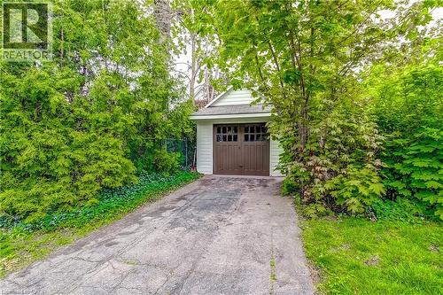 Detached single-car garage featuring light-colored siding and a brown garage door with window inserts - 18 Fairleigh Crescent, Hamilton, ON - Outdoor