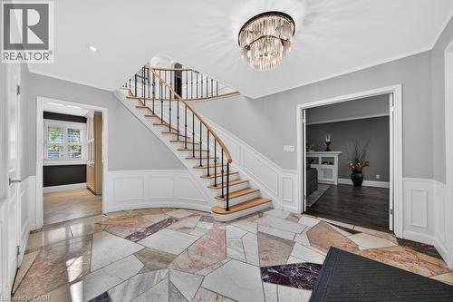 Grand foyer featuring a curved staircase with natural wood treads and iron balusters - 25 Braemar Place, Hamilton, ON - Indoor Photo Showing Other Room