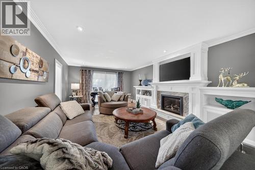 Living area featuring a gas fireplace with a stone surround, white mantel, and built-in shelving - 25 Braemar Place, Hamilton, ON - Indoor Photo Showing Living Room With Fireplace