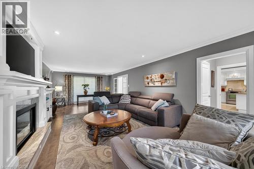 Spacious living area featuring wood-finish flooring, a white mantel fireplace with a dark insert, recessed lighting, and crown molding - 25 Braemar Place, Hamilton, ON - Indoor Photo Showing Living Room With Fireplace